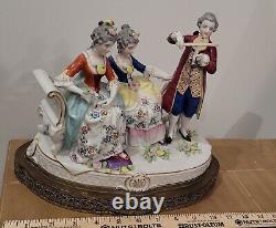 Figurine allemande antique d'un homme jouant du violon avec des dames sur un canapé sur une base en laiton en porcelaine de taille large