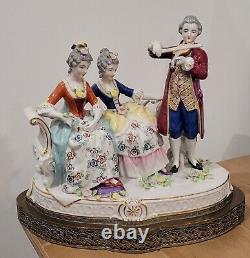 Figurine allemande antique d'un homme jouant du violon avec des dames sur un canapé sur une base en laiton en porcelaine de taille large