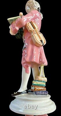 Figurine en porcelaine Goldscheider de Mozart lisant un livre avec un violon en costume rose - Antiquité