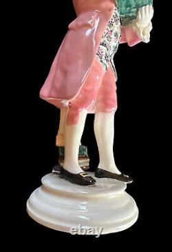 Figurine en porcelaine Goldscheider représentant Mozart lisant un livre avec un violon, en costume rose, antique.