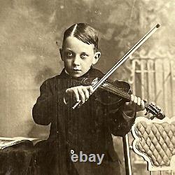 Photographie d'un petit garçon effrayant jouant du violon dans un cabinet de curiosités ancien à New York NY.