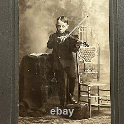 Photographie d'un petit garçon effrayant jouant du violon dans un cabinet de curiosités ancien à New York NY.