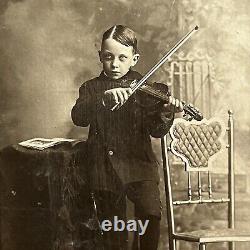 Photographie d'un petit garçon effrayant jouant du violon dans un cabinet de curiosités ancien à New York NY.